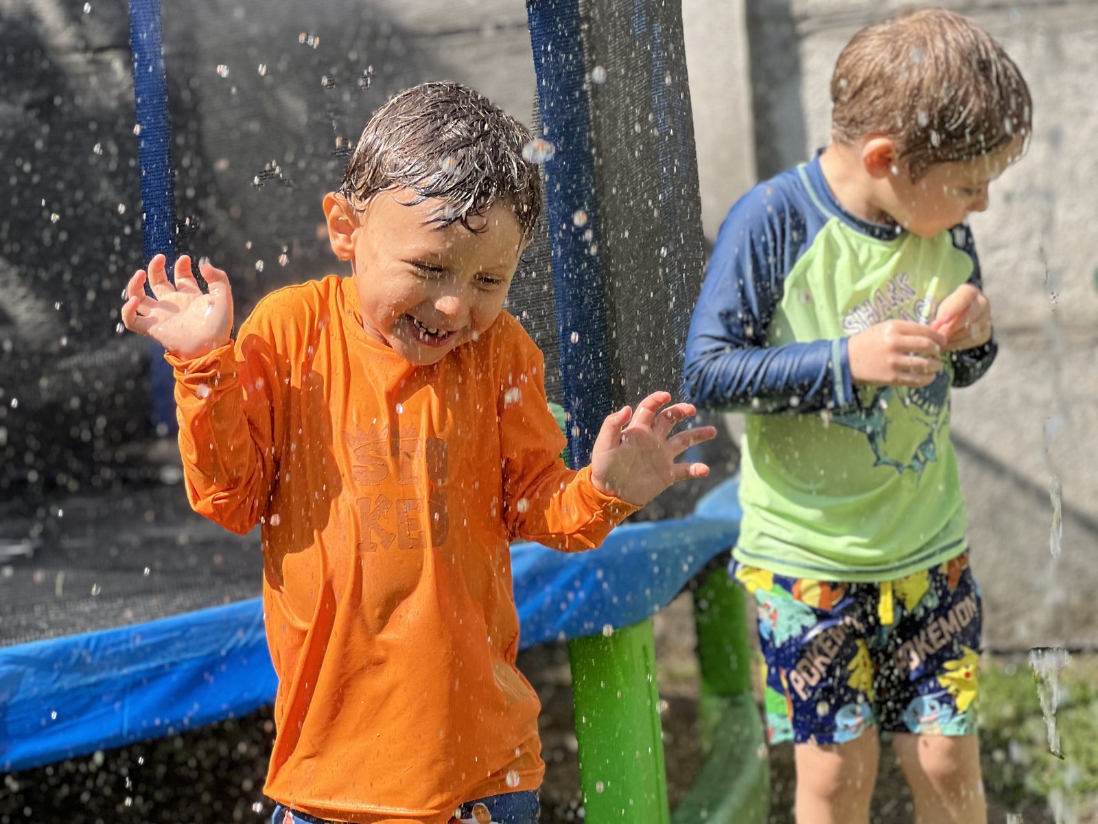Niños jugando bajo pequeñas gotas de agua durante el verano