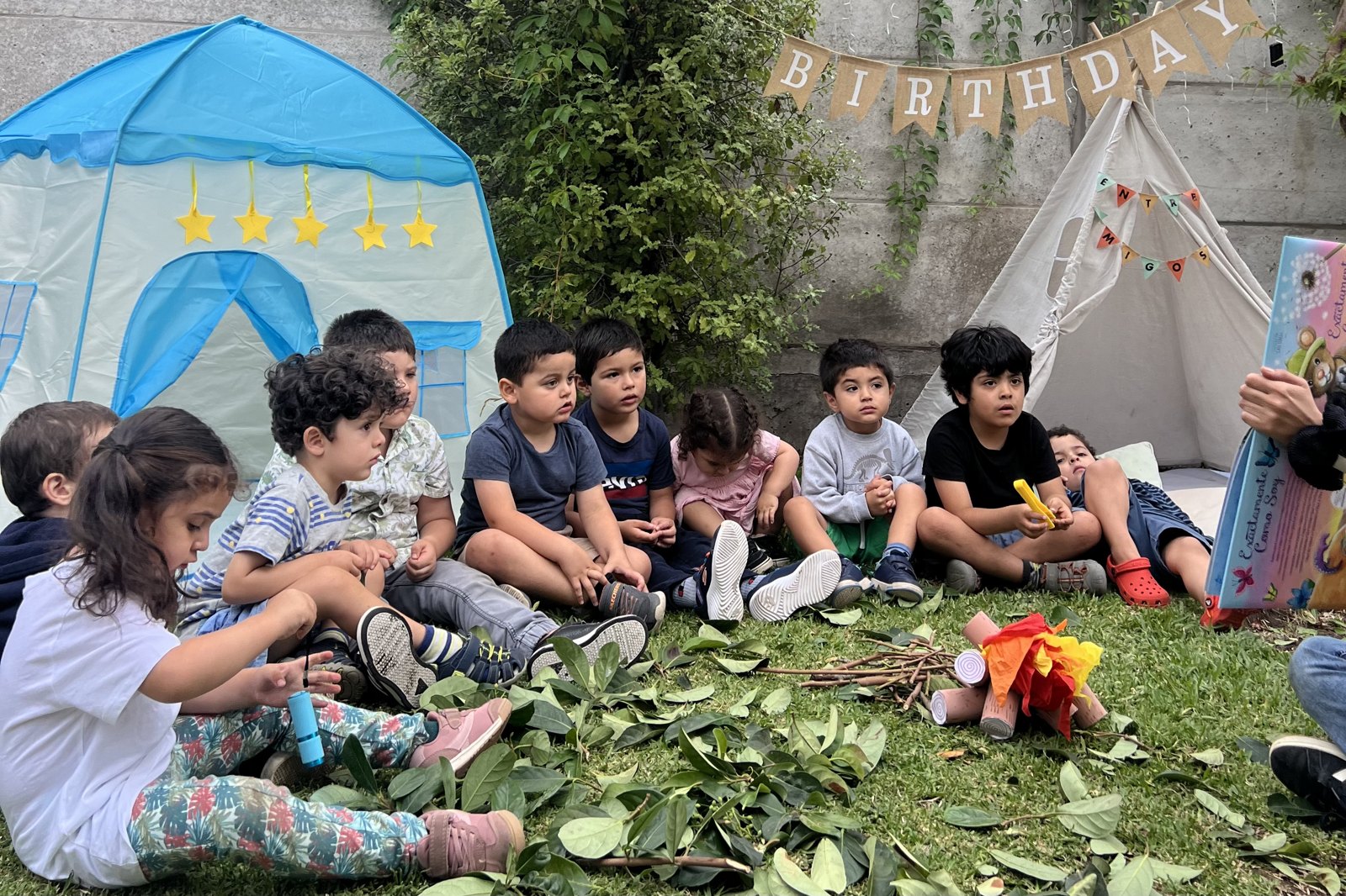 Niños y niñas escuchando un cuento juntos en el patio de Entre Amigos